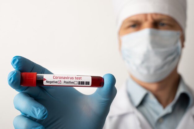 Mężczyzna pracownik medyczny trzyma negatywny test koronawirusa w ręku. Coraz częściej pojawiają się testy negatywne. Koniec pandemii koronawirusa.