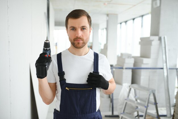 Zdjęcie mężczyzna pracownik płyt kartonowo-gipsowych instaluje arkusz płyt gipsowo-kartonowych do ściany