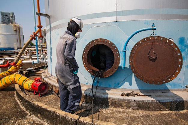 Mężczyzna pracownik w obszarze interfejsu oleju chemicznego z węglem w zbiorniku bezpieczeństwo w ograniczonej przestrzeni