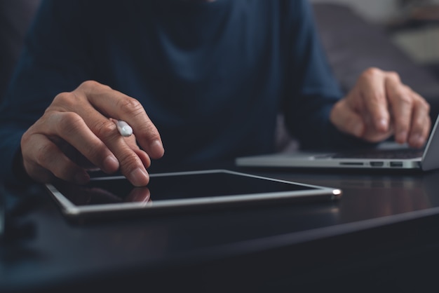 mężczyzna pracujący na cyfrowym tablecie i laptopie w domowym biurze