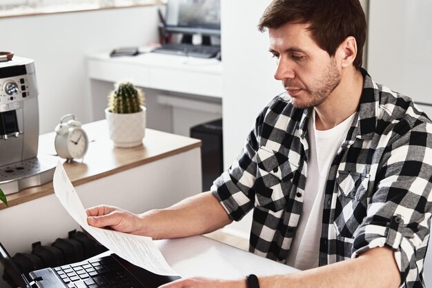 Zdjęcie mężczyzna pracujący w domu z laptopem i smartfonem koncepcja biznesu online praca zdalna