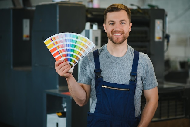 Zdjęcie mężczyzna pracujący w drukarni z papierem i farbami