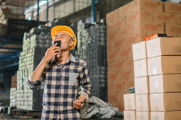 Zdjęcie mężczyzna pracujący w fabryce całuje telefon komórkowy po otrzymaniu dobrych wiadomości podczas pracy w magazynie