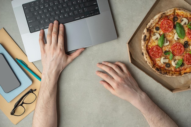 Mężczyzna pracuje i je pizzę Widok z góry ręce na pulpicieDostawa pizzy