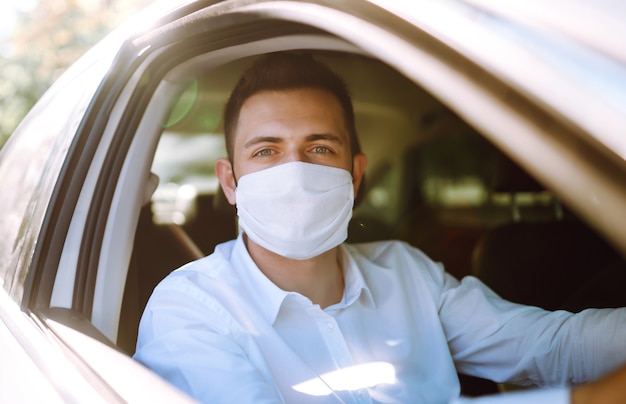 Mężczyzna Prowadzący Samochód Zakłada Maskę Medyczną Podczas Epidemii W Mieście Kwarantanny.