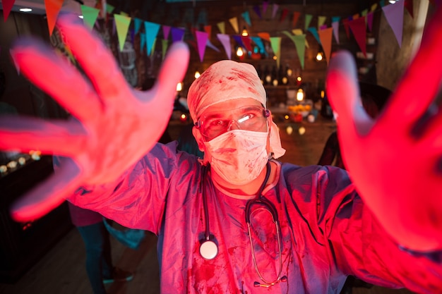 Mężczyzna przebrany za lekarza bawiącego się na imprezie z okazji halloween. Halloweenowa impreza w nocnym klubie.