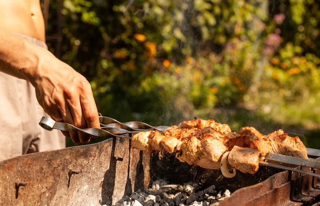 Zdjęcie mężczyzna przygotowuje pyszne szaszłyki wieprzowe z grilla na grillu