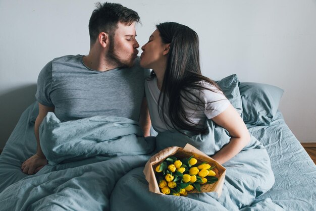 Mężczyzna przynosi kwiaty do łóżka niespodzianka dla dziewczyny rano romantyczna koncepcja