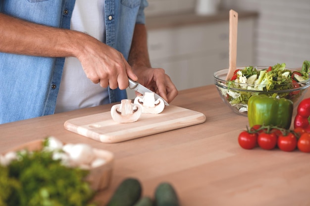 Mężczyzna ręce krojenie warzyw na sałatkę w kuchni przycięte zdjęcie