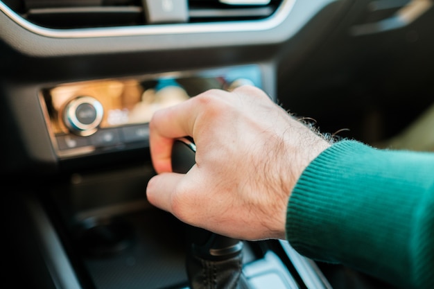 Zdjęcie mężczyzna ręcznie zmieniający skrzynię biegów w nowoczesnym automacie zmieniającym drążek ręczny lub automatyczny