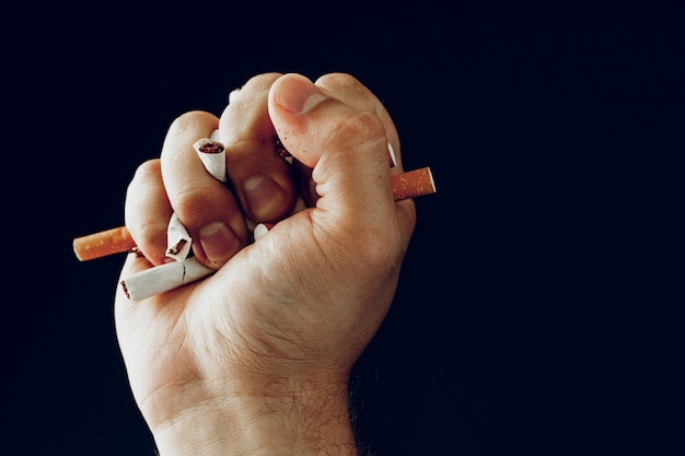 Mężczyzna ręka łamie papierosy z bliska rzucając zły nawyk