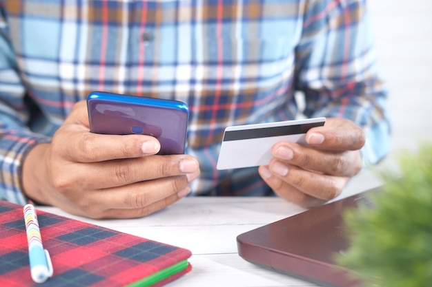 Mężczyzna ręka trzyma kartę kredytową i za pomocą inteligentnego telefonu zakupy online