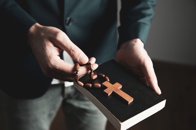 Zdjęcie mężczyzna ręka trzyma krzyż z biblią