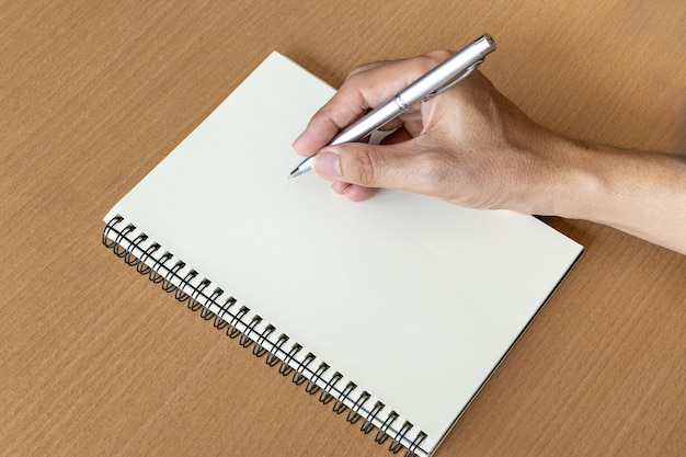 Mężczyzna ręka z piórem przygotowywa pisać na notatniku