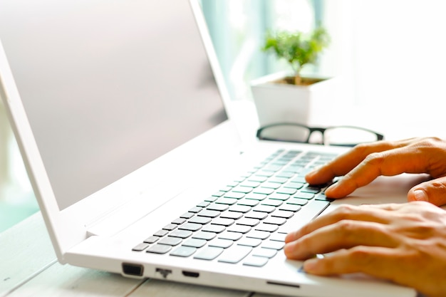 Mężczyzna ręki używać laptop z pustym ekranem na biurku w domowym wnętrzu.