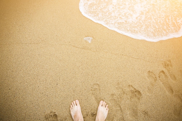 Mężczyzna relaksuje się boso na plaży Nogi faceta na piasku Fale od strony oceanu Letnie wakacje Koncepcja podróży