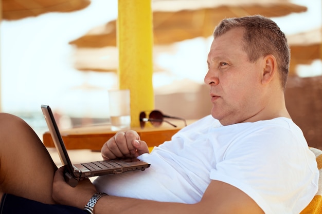 Mężczyzna relaksuje z laptopem przy miejscowością nadmorską
