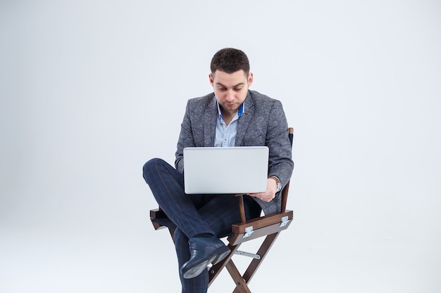 Mężczyzna reżyser dyrektor biznesmen siedzi na krześle studiując dokumenty. Patrzy na ekran laptopa. Nowy projekt biznesowy.
