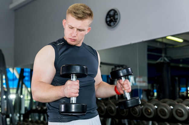 Mężczyzna robi ćwiczenie z hantlami na biceps na siłowni