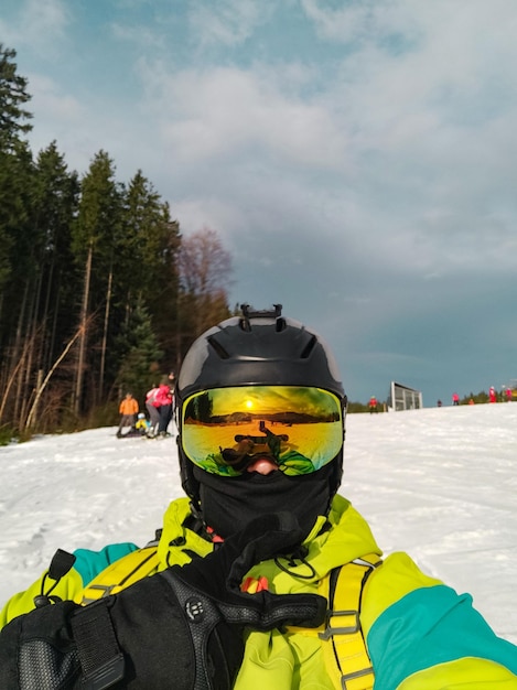 Mężczyzna robi selfie w masce narciarskiej i okularach na śnieżnym wzgórzu
