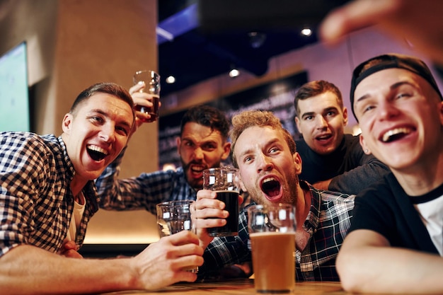 Zdjęcie mężczyzna robi sobie selfie przez telefon grupa ludzi w pubie bawi się w weekend