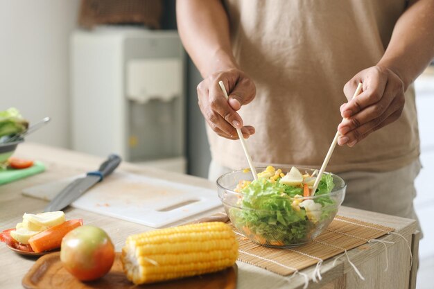 Mężczyzna robi świeżą wegetariańską sałatkę w kuchni w domu