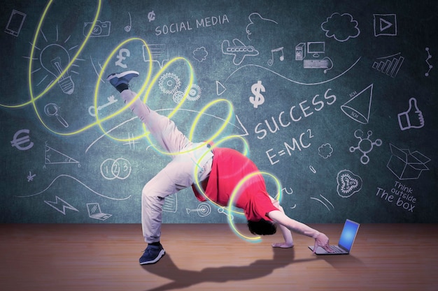 Mężczyzna robi taniec breakdance podczas korzystania z laptopa w klasie