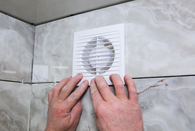 Mężczyzna robi wentylator ścienny w łazience Proces przywracania