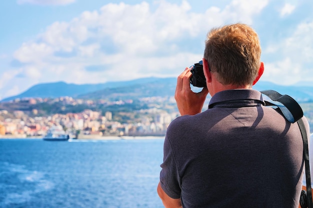 Mężczyzna robi zdjęcia Morza Śródziemnego i krajobrazu w Reggio Calabria, Włochy