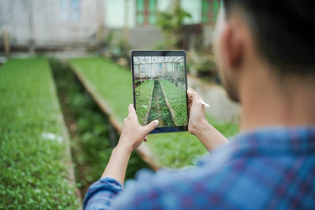Zdjęcie mężczyzna robi zdjęcie gospodarstwa za pomocą cyfrowego tabletu koncepcja fotografii cyfrowej rolnictwa