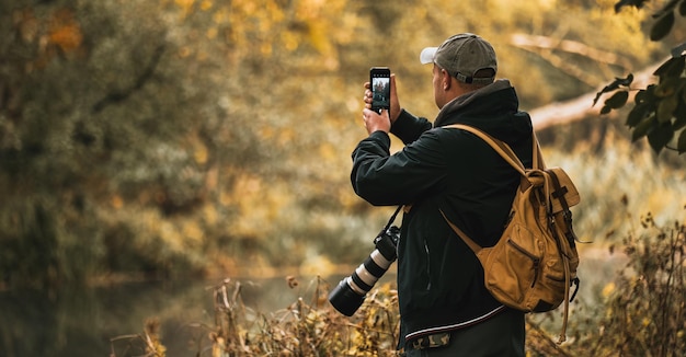 Mężczyzna robi zdjęcie na zewnątrz Profesjonalny fotograf robi zdjęcia krajobrazu i dzikiej przyrody Duży aparat