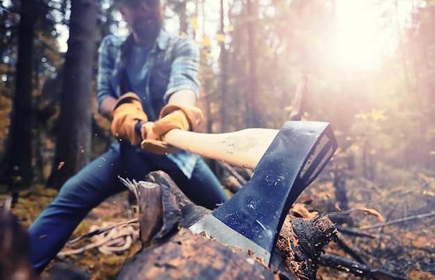 Mężczyzna robotnik siekierą rąbiący drzewo w lesie