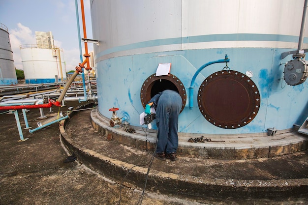 Mężczyzna robotnik w obszarze interfejsu zbiornika węgla chemicznego oleju w przestrzeni zamkniętej.