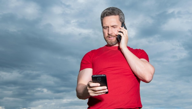 Mężczyzna rozmawia przez telefon ma na sobie czerwoną koszulkę z reklamą w miejscu na kopię Zdjęcie mężczyzny rozmawia przez telefon