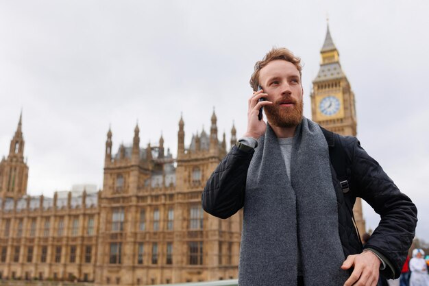 Mężczyzna rozmawia przez telefon, stojąc w pobliżu londyńskiego Big Bena