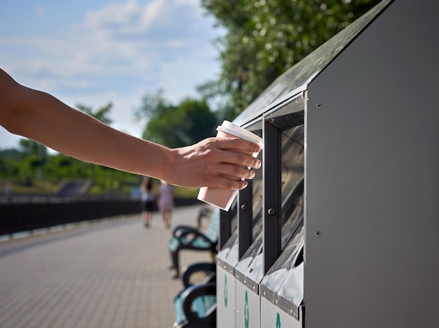 Mężczyzna rzuca papierową filiżankę kawy w koszu na odpady