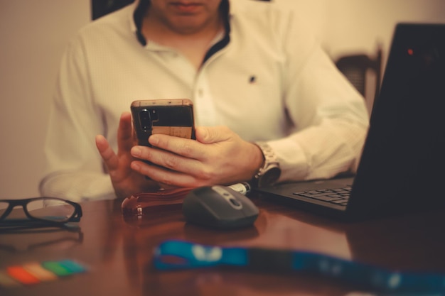 Mężczyzna siedzący na drewnianym stole i używający notatnika, wysyłający wiadomość tekstową.