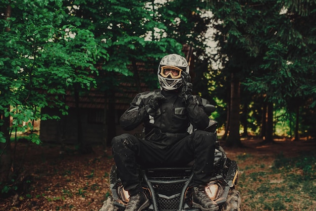 Mężczyzna siedzący na quadzie w lesie i przygotowujący się do jazdy