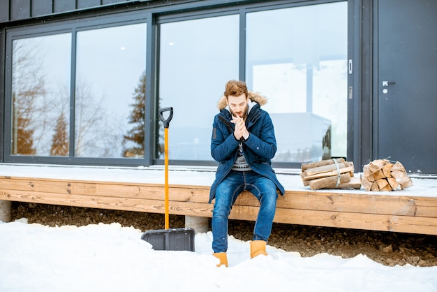 Mężczyzna siedzący zimą na tarasie nowoczesnego domu
