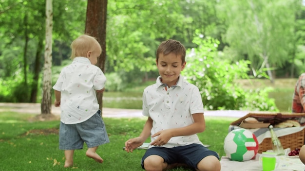 Zdjęcie mężczyzna siedzi na kocu z dziećmi w parku dzieci bawiące się bańkami mydlanymi