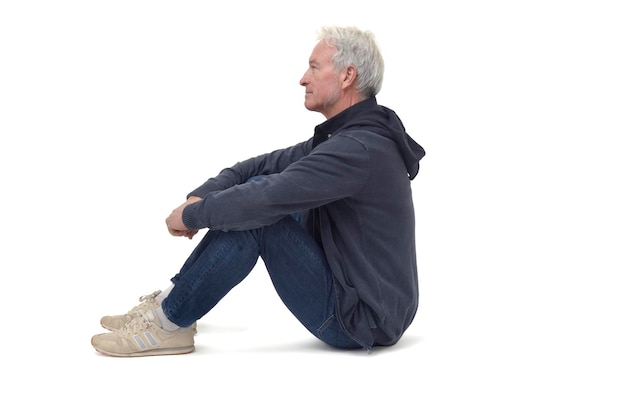 Mężczyzna siedzi na podłodze ze złożonymi nogami i patrzy na odległość na białym tle
