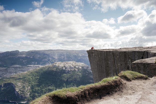 Mężczyzna siedzi na Preikestolen, Pulpit Rock w pięknym krajobrazie górskim Norwegii