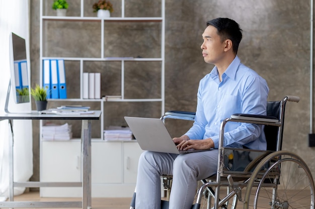 Mężczyzna siedzi na wózku inwalidzkim mężczyzna z niepełnosprawnością porusza się na wózku i pracuje w biurze firmy pracując z zespołem firmy i mając w zespole osobę niepełnosprawną