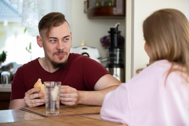 Mężczyzna siedzi ze swoją dziewczyną w kuchni i je śniadanie.