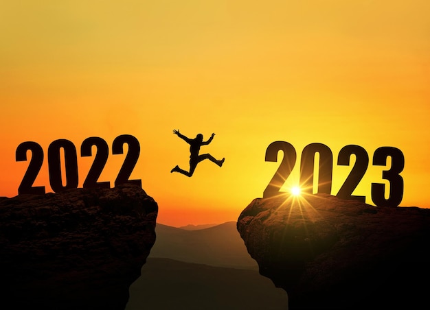 Mężczyzna skaczący na klifie 2023 nad przepaścią o niesamowitym zachodzie słońca Koncepcja noworoczna Symbol rozpoczęcia i powitania szczęśliwego nowego roku 2023 Ludzie wkraczają w rok 2023 twórczy pomysł
