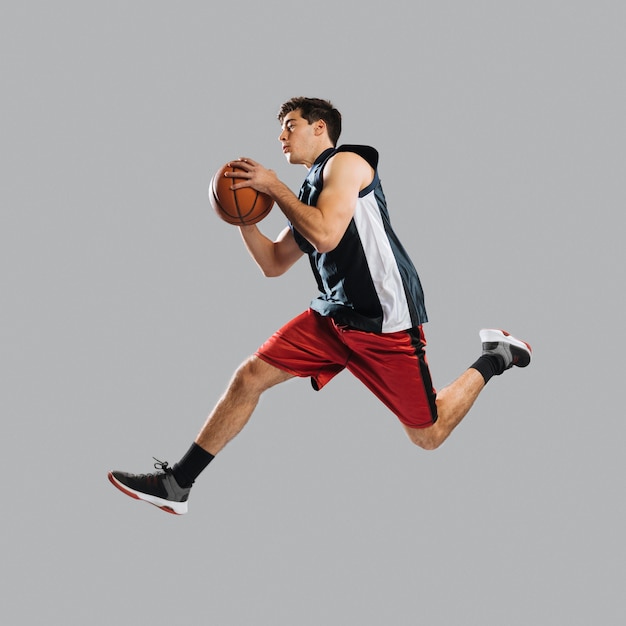 Zdjęcie mężczyzna skacze trzymając koszykówkę