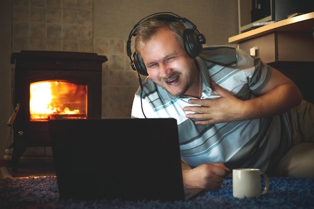 Mężczyzna śmieje się, patrząc na zawartość online na laptopie w nocy w saloniexA