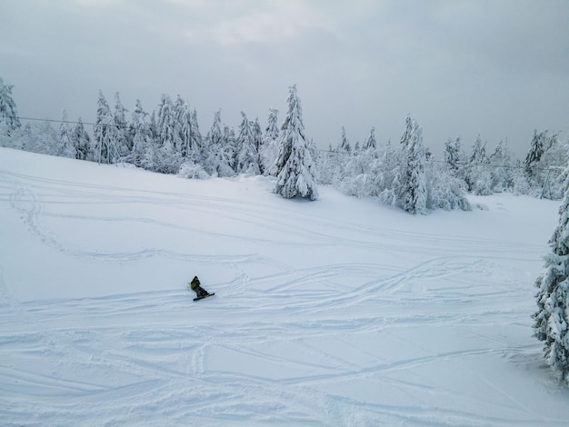 Mężczyzna snowboardzista cieszący się zachodem słońca nad górami