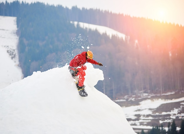 Mężczyzna Snowboardzista Jedzie Ze Szczytu Ośnieżonego Wzgórza Z Snowboardem W Zimowym Ośrodku Narciarskim