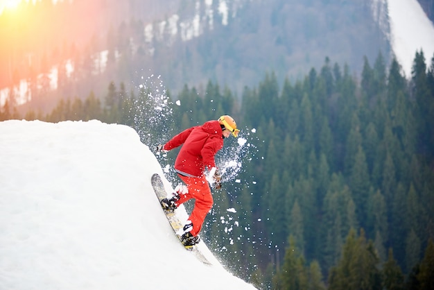 Mężczyzna Snowboardzista Jedzie Ze Szczytu Zaśnieżonego Stoku Z Snowboardem.